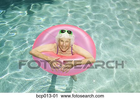 Stock Photography of Senior woman floating in a swimming pool. bcp013