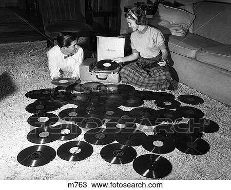 Stock Photo of 1950S Teen Couple Playing Many Records Spread Out On