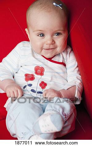 Nashville, tennessee, united states of america; a baby girl sitting on a red couch - 1877011