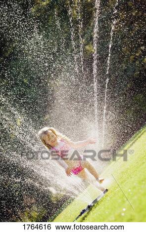 Kids jumping through lawn sprinkler Stock Photo: 29726084 