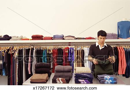 Stock Photo - Young woman buying clothes in a sale, Fat face clothing store, Norwich UK