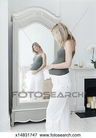 Pregnant Woman Looking At Her Reflection In A Mirror Stock Photo