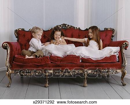 Stock Photo Of Three Well Dressed Young S And Boy Sit On Stock Photo Three Well Dressed Young S And Boy Sit On An Ornate Sofa