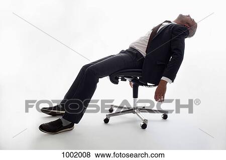An Exhausted Businessman Sleeping In An Office Chair An Exhausted Businessman Sleeping In An Office Chair