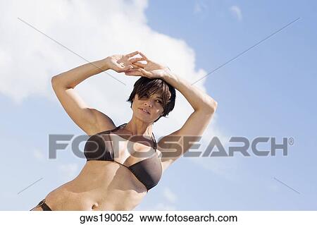 Low Angle View Of A Mid Adult Woman Standing With Her Hands Behind Her