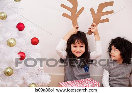 Dos niñas, preparación para navidad, juego, con, cartón, reno, cornamenta Dos niñas, preparación para navidad, juego, con, cartón, reno, cornamenta
