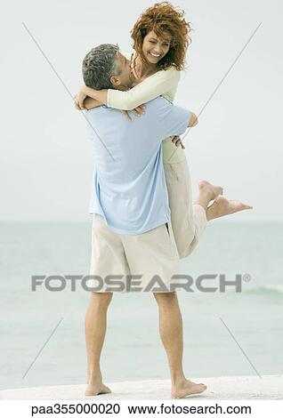 Mature Couple Man Picking Up Woman On Beach Stock Image Paa355000020