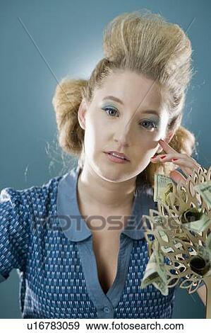 Stock Photograph - Young woman with blue Eyeshadow, money plant in foreground. Fotosearch - - u16783059