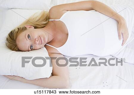 Stock Photo - Pregnant woman lying in bed smiling. Fotosearch - Search ...