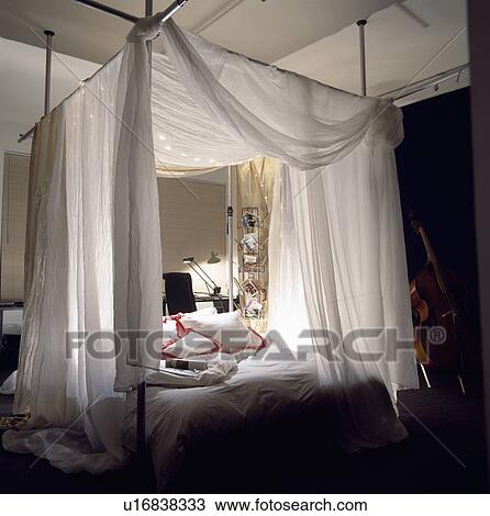 Four Poster Bed Drapes stock photo of white voile drapes on modern metal four-poster bed Four Poster Bed Drapes stock photo of white voile drapes on modern metal four-poster bed