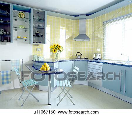 Stock Photography Of Pale Blue Folding Chairs At Ed Table In Pale Blue Folding Chairs At Ed Table In Modern Pastel Yellow Kitchen With Units