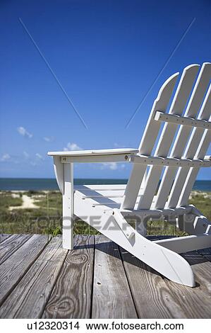 Stock Photo of Empty white adirondack chair on wooden deck ...