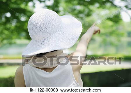Stock Photo - A woman wearing hat and pointing. Fotosearch