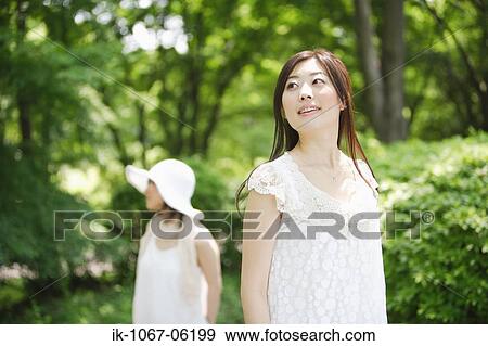 A young smiling woman standing in park View Large Photo Image Stock Photo - A young smiling woman standing in park. Fotosearch
