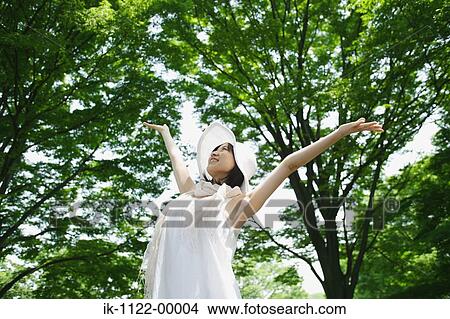 Picture - A young woman looking at green trees. Fotosearch