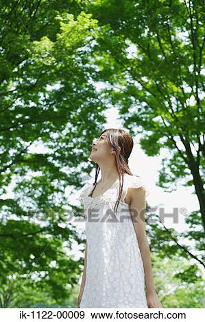 Stock Photo - A young woman looking at green trees. Fotosearch