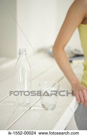 An open water bottle lying with glass of water View Large Photo Image Picture - An open water bottle lying with glass of water . Fotosearch