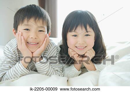 Asian children lying on a bed View Large Photo Image Stock Photo - Asian children lying on a bed. Fotosearch