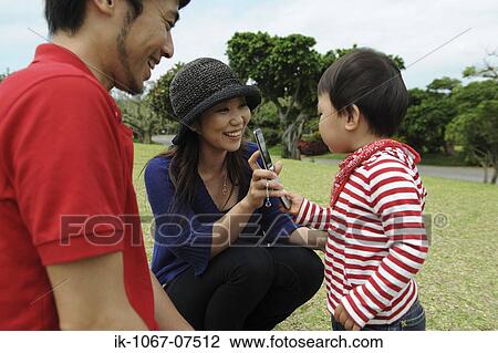 Asian couple showing cell phone to his son View Large Photo Image Stock Image - Asian couple showing cell phone to his son. Fotosearch