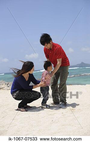 Stock Image - Asian family enjoying on beach. Fotosearch