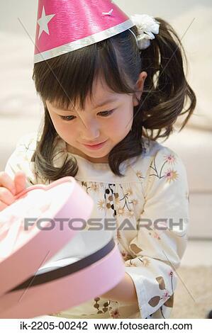 Stock Image - Asian girl opening her birthday present. Fotosearch