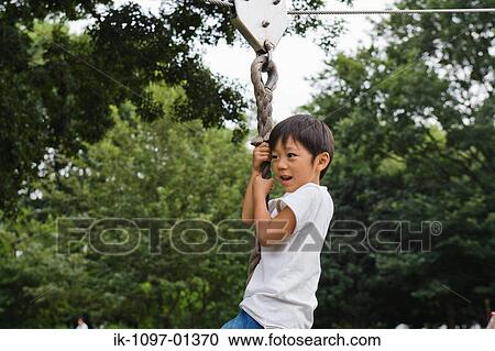 Boy hanging on zip-line in a park View Large Photo Image Stock Image - Boy hanging on zip-line in a park. Fotosearch