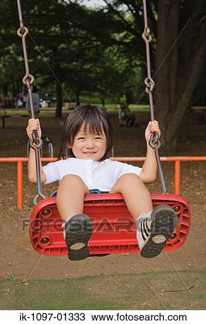 Stock Image - Boy in a park swinging on a playground swing. Fotosearch