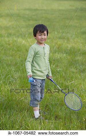 Stock Image - Boy playing badminton in park. Fotosearch