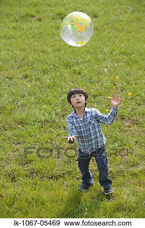 Boy playing with a ball in park View Large Photo Image Stock Photo - Boy playing with a ball in park. Fotosearch