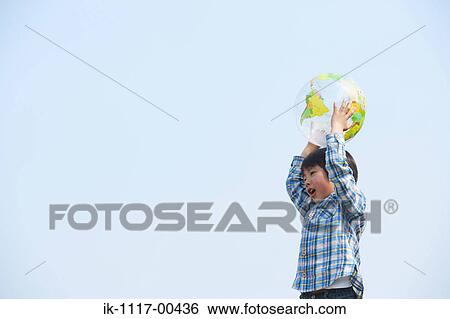 Boy playing with ball against blue sky View Large Photo Image Stock Photograph - Boy playing with ball against blue sky . Fotosearch
