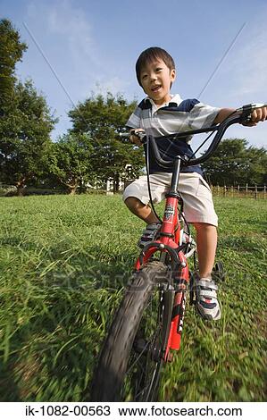 Stock Image - Boy riding bicycle in park. Fotosearch