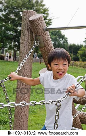 Boy standing on jungle gym in a park View Large Photo Image Stock Image - Boy standing on jungle gym in a park. Fotosearch