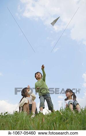 Boy throwing paper airplane while girls sitting beside View Large Photo Image Stock Image - Boy throwing paper airplane while girls sitting beside. Fotosearch