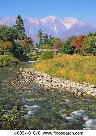 Stock Image - Bridge crossing river with scenic mountains in background. Fotosearch