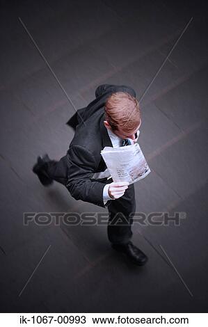 Stock Image - Businessman Running while Holding Newspaper. Fotosearch