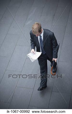 Businessman Walking and Reading Newspaper View Large Photo Image Stock Image - Businessman Walking and Reading Newspaper. Fotosearch