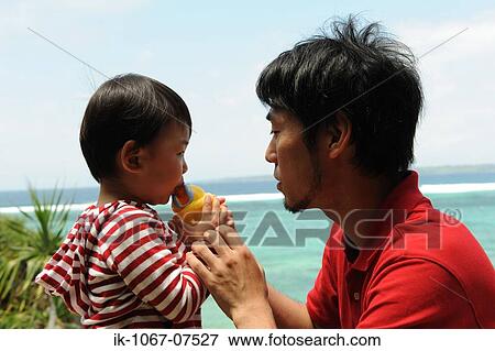 Stock Photo - Child drinking water with his father on beach. Fotosearch