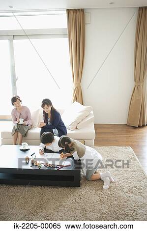 Stock Photography - Child painting with family in living room. Fotosearch
