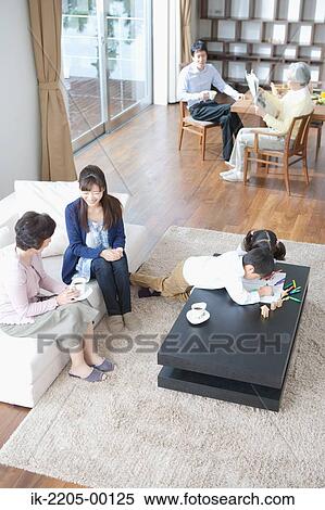 Stock Photography - Child painting with family in living room. Fotosearch