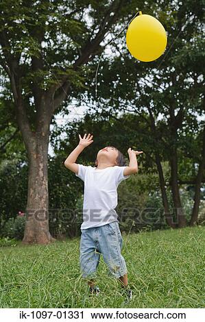 Child playing with a ballon in park View Large Photo Image Stock Image - Child playing with a ballon in park. Fotosearch