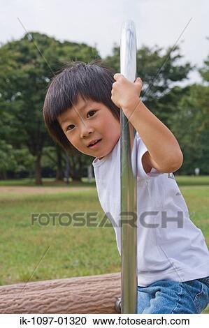Child standing against pole in a park View Large Photo Image Stock Image - Child standing against pole in a park. Fotosearch