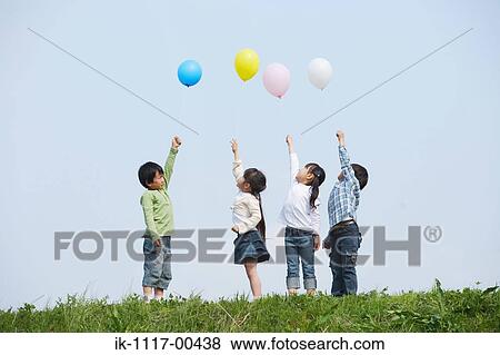 Stock Photo - Children holding colorful balloons in park. Fotosearch