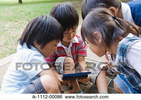 Stock Photograph - Children playing handheld videogame. Fotosearch