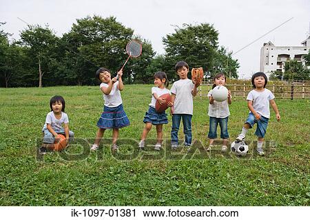 Stock Image - Children playing with sports equipments in a park. Fotosearch