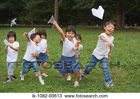 Children running and throwing paper aeroplanes in park View Large Photo Image Stock Image - Children running and throwing paper aeroplanes in park. Fotosearch