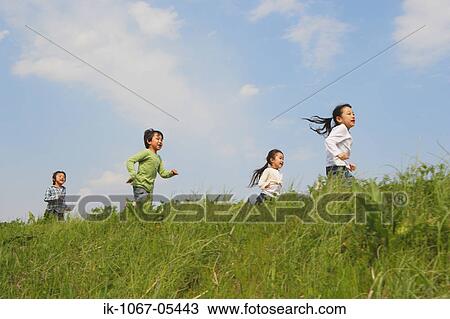 Stock Image - Children running in park together. Fotosearch