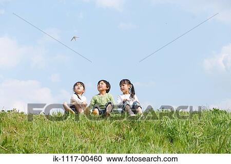 Children sitting in park and looking at flying paper airplane View Large Photo Image Stock Image - Children sitting in park and looking at flying paper airplane . Fotosearch