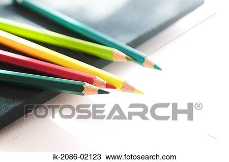 Stock Image - Colorful pencils lying on drawing book. Fotosearch