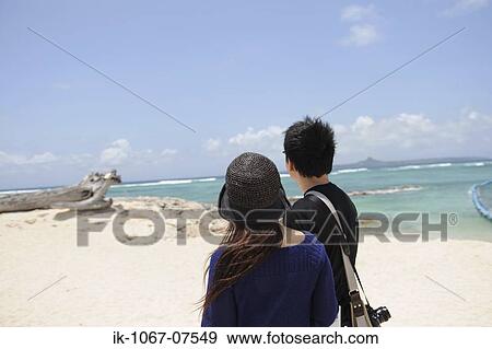 Stock Photo - Couple on beach looking out to sea. Fotosearch