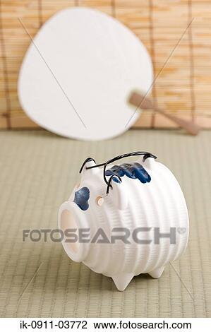 Stock Image - Empty piggy bank with traditional folding fan. Fotosearch